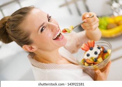 Happy Young Housewife Eating Fruits Salad . Rear View