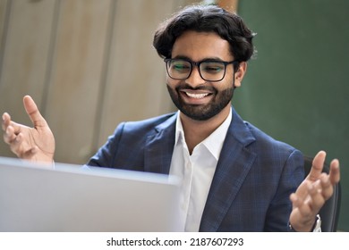 Happy young indian business man investor executive wearing suit looking at laptop computer feeling excited about achievement, online success, crypto market growth, celebrating win and leadership. - Powered by Shutterstock