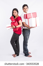 Happy And Young Indian Couple With Christmas Gifts, Over White Background