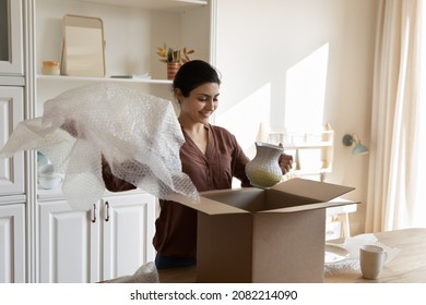 Happy Young Indian Ethnicity Woman Unpacking Huge Cardboard Box From Internet Store, Feeling Excited Of Receiving Vase, Enjoying Improving Interior, Purchasing Decorations And Ware For New Home.