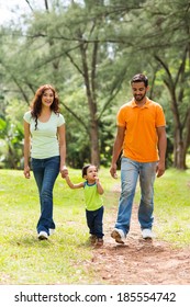 Happy Young Indian Family Walking In Park