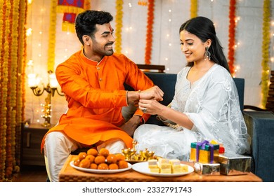 Happy young indian girl tying rakhi to brother hand during raksha bandhan festival at home - concept of indian culture, relationship and occasion - Shutterstock ID 2332791743
