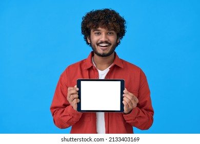 Happy young indian man showing tablet, computer big mockup white blank empty template screen isolated on blue background presenting holding pad website offer or application ads concept.