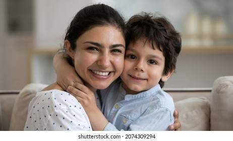 Happy young Indian mom hugging cute little smiling son with cheek touch, looking at camera. Grateful mother embracing kid tightly with love, affection, tenderness. Family, motherhood concept