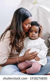 Happy Young Indian Mother Playing Kissing Mixed Race Black Baby Girl Daughter. Family Mixed Race People Mom And Kid Together Hugging Embracing At Home. Ethnic Diversity Family. 