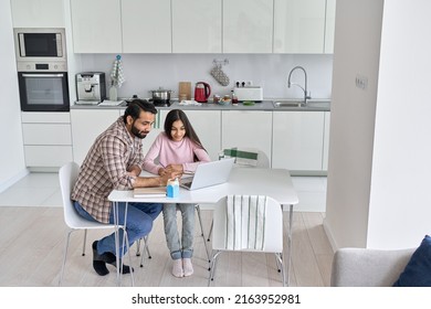 Happy Young Indian Parent Father Helping Teenage Child Daughter Distance Learning At Home. Teen School Kid Girl Studying In Kitchen With Dad Having Virtual Online Class Together. Remote Education.