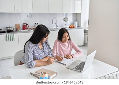 Happy Young Indian Parent Mother Helping Teenage Child Daughter Remote Learning Online Virtual Class On Laptop Together At Home. Teen School Kid Girl Studying In Kitchen With Mum Sit At Kitchen Table.