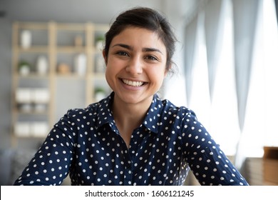 Happy young indian woman blogger applicant teacher sit at home office look at camera doing online job interview during video chat conference call record vlog teaching on webinar in app, webcam view