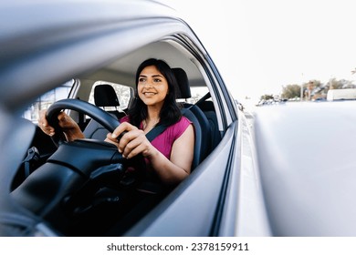 Happy young indian woman driving new car in the city. Rental car service concept - Powered by Shutterstock