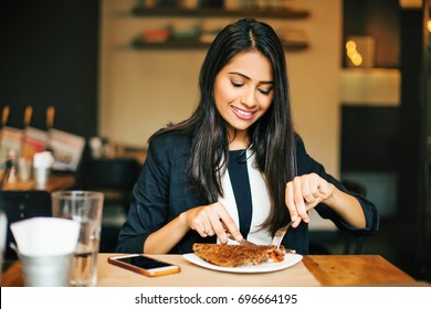 A happy young Indian woman having a pancake in a restaurant - Powered by Shutterstock