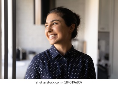 Happy Young Indian Woman Look In Window Distance Dreaming Or Imagining Happy Bright Future Career Opportunities Or Success. Overjoyed Millennial Ethnic Female Visualize At Home. Vision Concept.