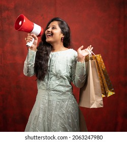 Happy Young Indian Woman Making Announcement On Megaphone About Online Or E-commerce Sales By Holding Shopping Bags - Concept Of Promotion, Special Offers During Festivals