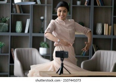 Happy young Indian woman recording ballet dance moves on cellphone web camera, doing rehearsal or streaming live video in social network at home, sharing professional skills online. - Powered by Shutterstock