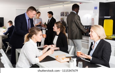 Happy Young International Group Of Business People Chatting While Enjoying Coffee In Break Room