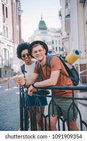 happy young interracial couple of travelers with paper cups of coffee