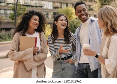 Happy young interracial students chatting with each other after class standing outside. Guy and girls wear casual clothes to study. Lifestyle concept, sincere emotions - Shutterstock ID 2201882961