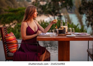 Happy Young Lady Eating Delicious Food In Fine Dining Outdoor Restaurant. Sexy Girl In Elegant Evening Dress On Date. Romantic Dinner On Sunset. Concept Of Proposal Or Honeymoon