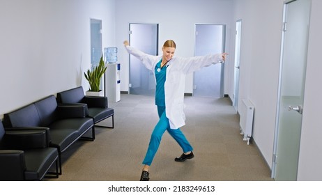 Happy and young lady family doctor dancing in front of the camera in the hospital corridor she are so excited - Powered by Shutterstock