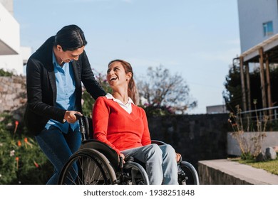 Happy young latin woman in wheelchair and her friend having fun outdoors in Mexico
