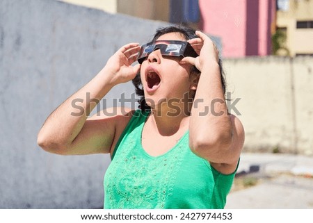 Happy young latina woman with solar eclipse glasses, watching a solar eclipse