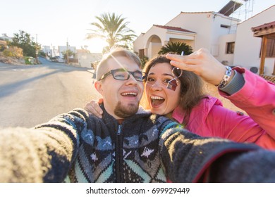 Happy young laughing cheerful couple man and woman handing their new home keys in front of a house