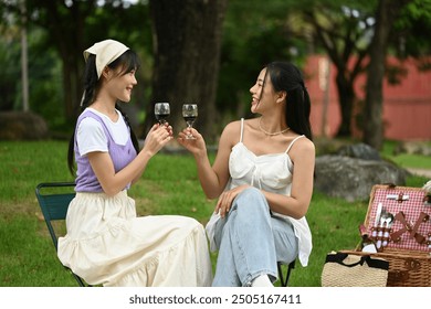 Happy young lesbian couples having fun outdoor and toasting with wine glasses at picnic. - Powered by Shutterstock