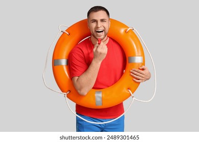 Happy young lifeguard with lifebuoy and whistle on white background - Powered by Shutterstock