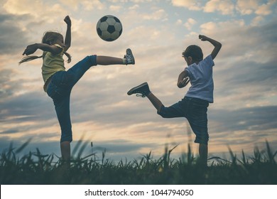 Happy Young Little Boy And Girl Playing In The Field  With Soccer Ball.  Kids Having Fun Outdoors. Concept Of Sport.