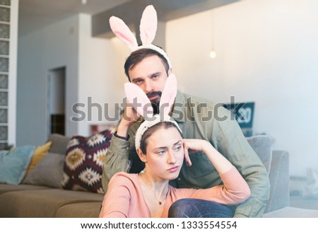 Happy young loving couple bonding to each other with pink rabbit ears on head. Funny family preparing for Easter