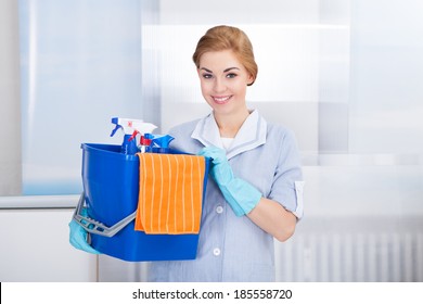 Happy Young Maid Holding Bucket With Cleaning Supplies