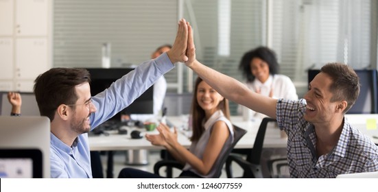 Happy young male colleagues giving high five, celebrate corporate success, team of office workers applaud, good teamwork results, business achievement, satisfied, motivated by victory