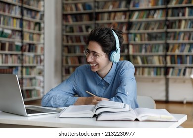 Happy Young Male Jewish Student In Eyeglasses Wearing Headphones, Watching Interesting Educational Lecture Or Webinar, Studying On Online Courses, Writing Notes Improving Knowledge, E-learning.