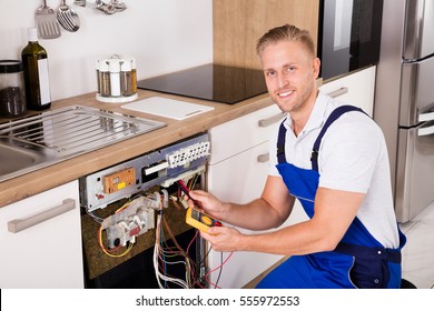 Happy Young Male Technician Checking Dishwasher With Digital Multimeter