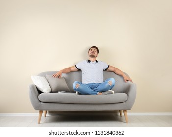 Happy Young Man With Air Conditioner Remote At Home