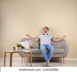 Happy Young Man With Air Conditioner Remote At Home