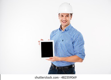 Happy young man architect in building helmet holding blank screen tablet
