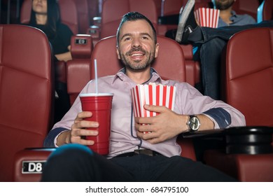 Happy Young Man With A Beard Hugging A Combo Of Soda And Popcorn While Watching A Movie At The Cinema Theater