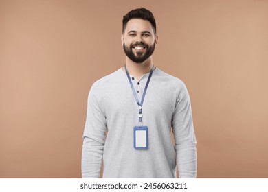 Happy young man with blank badge on beige background - Powered by Shutterstock