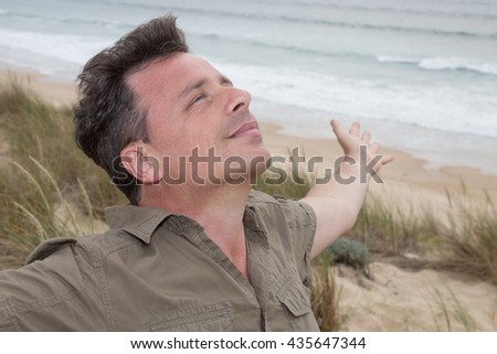 Happy young man breathing deep with handsup feels free at the beach