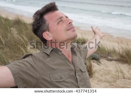 Happy young man breathing deep with handsup feels free at the beach