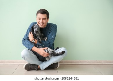 Happy Young Man With Cute Dog Sitting Near Color Wall