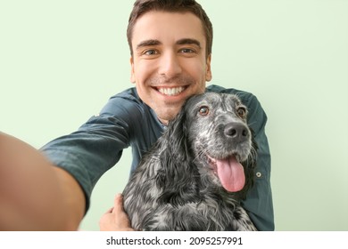 Happy young man with cute dog taking selfie on color background - Powered by Shutterstock