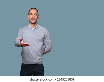 Happy young man doing a gesture of welcome with his hand - Shutterstock ID 2245205839
