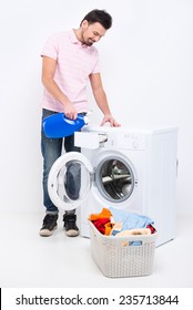 Happy young man is doing laundry at home, on the white background. - Shutterstock ID 235713844