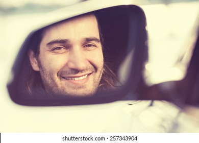 Happy Young Man Driver Looking In Car Side View Mirror, Making Sure Line Is Free Before Making A Turn. Positive Human Face Expression Emotions. Safe Trip Journey Driving Concept