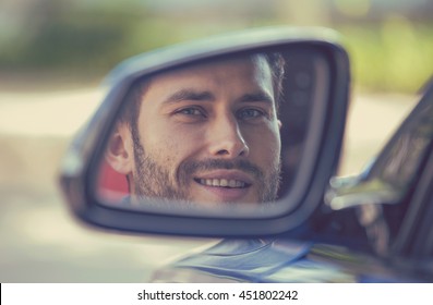 Happy Young Man Driver Looking In Car Side View Mirror, Making Sure Line Is Free Before Making A Turn. Positive Human Face Expression Emotions. Safe Trip Journey Driving Concept
