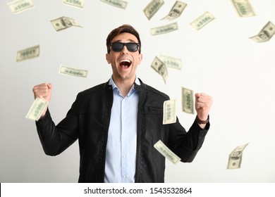 Happy young man and falling dollar banknotes on white background