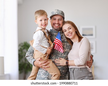 Happy young man father in military uniform reunited with his beautiful american family, hugging with smiling wife and cute kid son with flag of United States in hand, meeting daddy from US army at hom