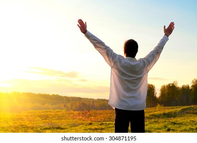 Happy Young Man With Hands Up On The Nature Background