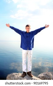 Happy Young Man With Hands Up On The Seaside Background